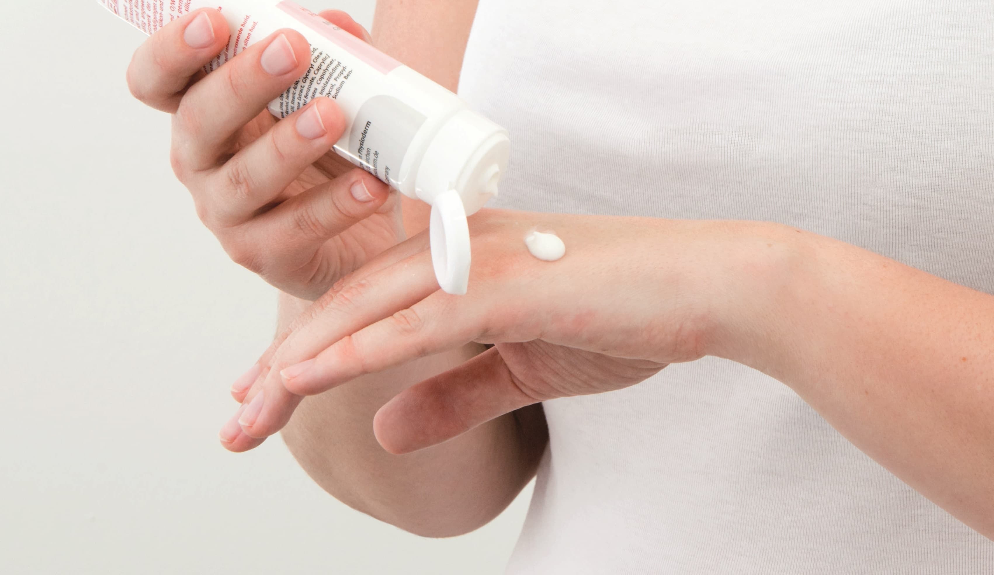 Hände eincremen zur Handpflege Wir sehen Frauenhände, die sich die Hände eincremen. Creme wir gerade auf den Handrücken der einen hand aufgetragen aus einer Cremetube