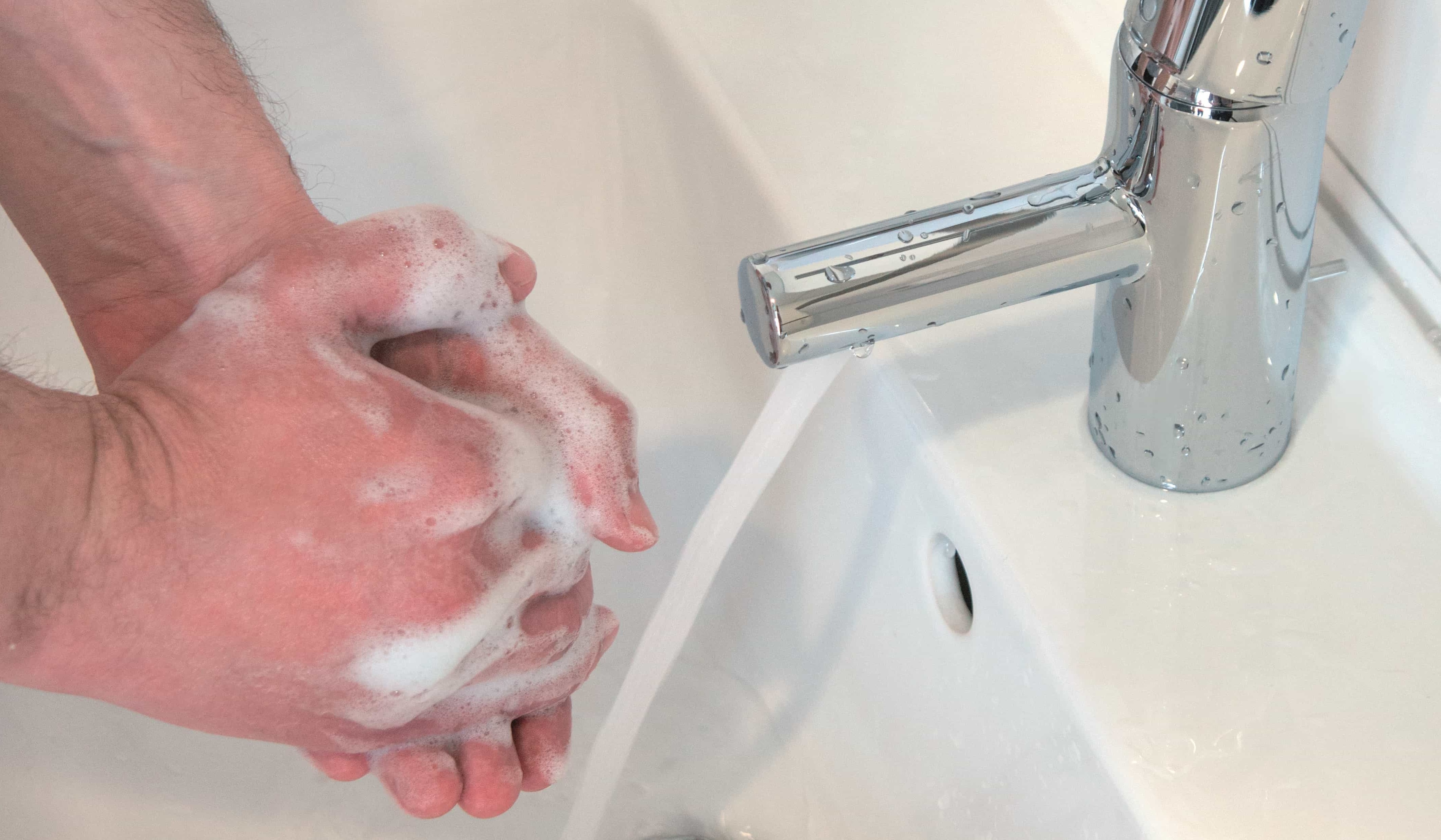 Händewaschen nicht vergessen Zwei Hände die mit viel Schaum Hände Waschen und einem fliessenden Wasserhahn