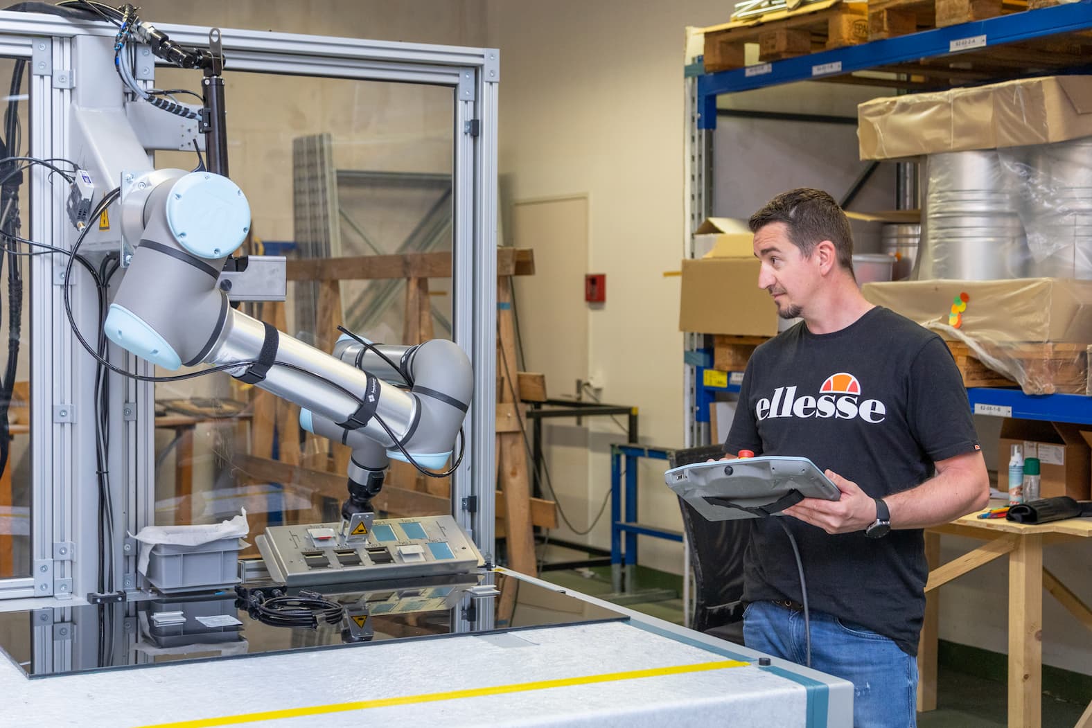 Roboterarm am Arbeiten Wir sehen einen Mann der mit einer Fernbedienung einen Roboterarm bedient